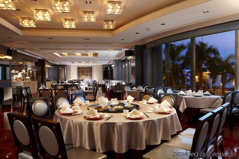 Ambassador Hotel Kaohsiung Exterior foto The photo depicts an elegant restaurant interior. It features round tables, each covered with white tablecloths and set with dishes and utensils, suggesting a formal dining experience. The restaurant has a modern and sophisticated design, with a well