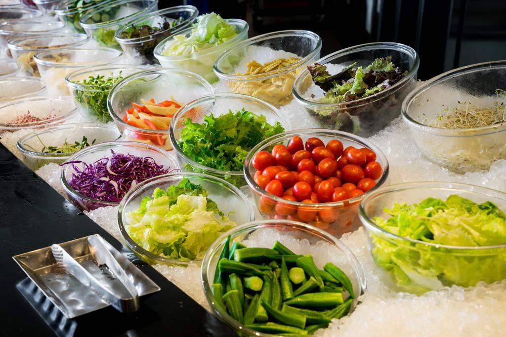 Ambassador Hotel Kaohsiung Exterior foto The photo displays a vibrant array of fresh vegetables and greens arranged in clear bowls on a bed of ice. The selection includes various leafy greens, chopped vegetables, and colorful ingredients. There are items like cherry tomatoes, purple cabbage