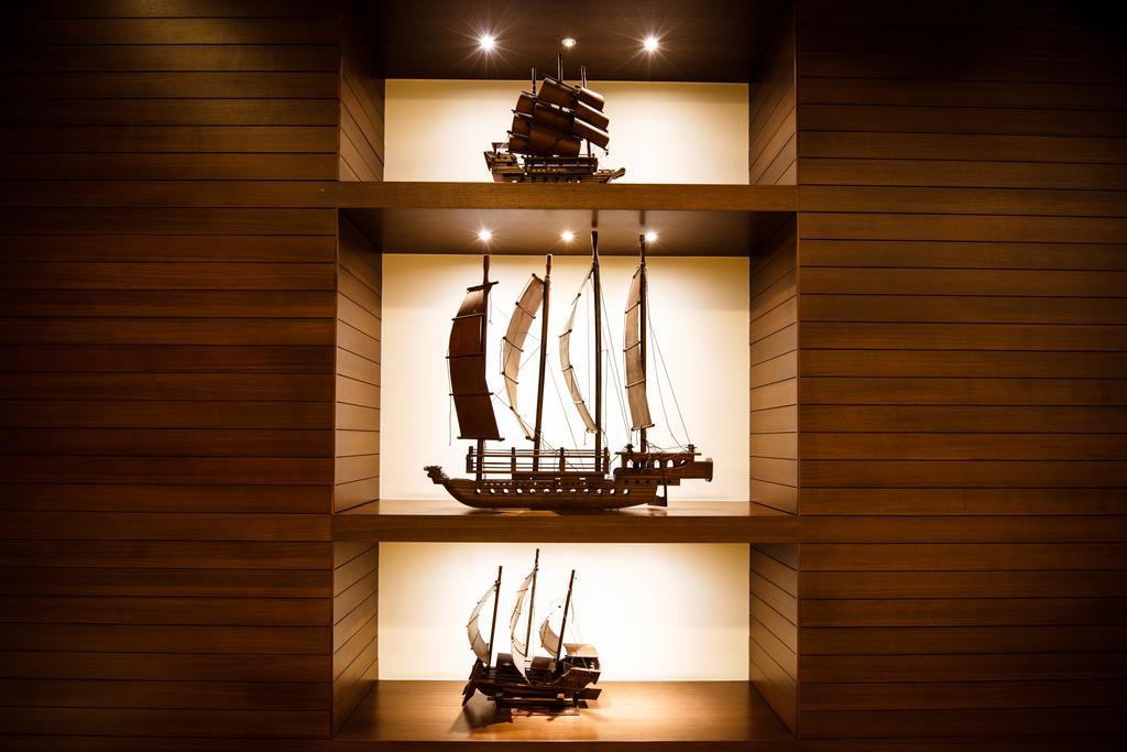 Ambassador Hotel Kaohsiung Exterior foto The photo displays three model ships arranged on shelves with a warm wood background. Each ship has distinct features and varying sizes, showcasing different designs. The top ship has a traditional Asian style with sails, the middle ship appears to b