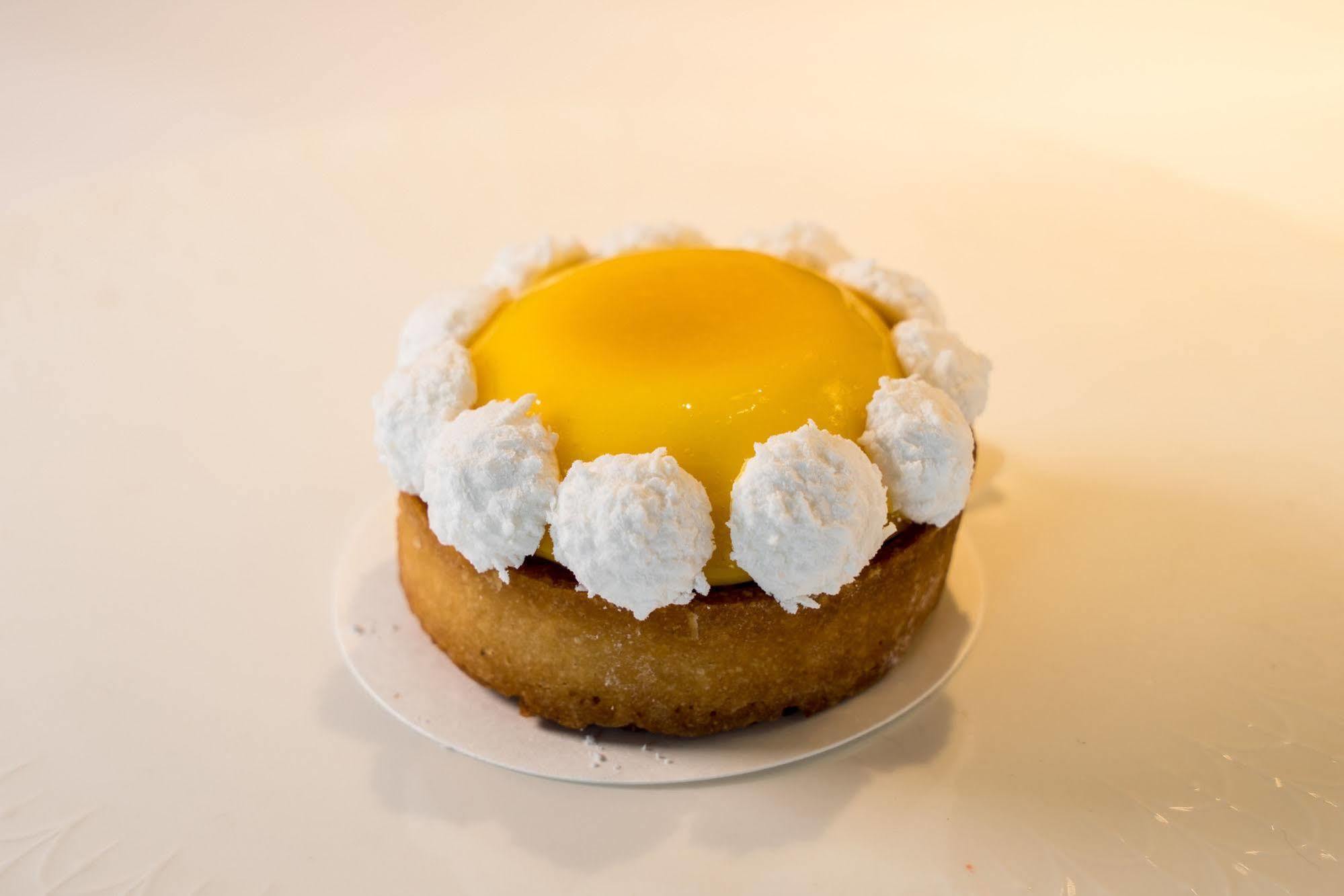 Ambassador Hotel Kaohsiung Exterior foto The photo showcases a round dessert, likely a tart or mini cake. The base appears to be a golden-brown, crumbly crust. It is topped with a bright yellow custard or gel-like layer, which gives it a vibrant appearance. Surrounding the yellow center is 
