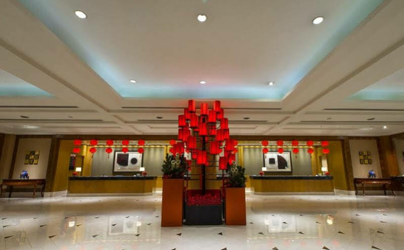 Ambassador Hotel Kaohsiung Exterior foto The photo shows a hotel lobby with a modern and elegant design. In the center, there is a striking red display, likely made up of lanterns or decorative elements, creating a vibrant focal point. The lobby features a polished floor that reflects the l